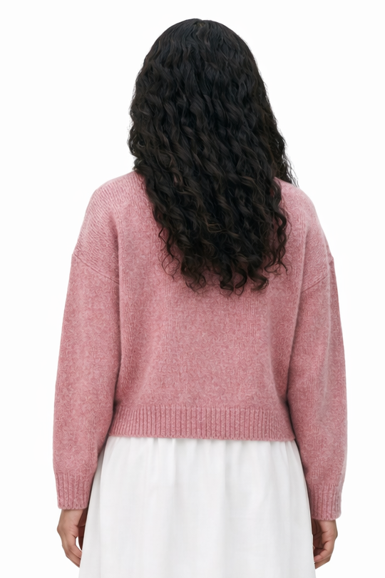 Person wearing a pink sweater and white skirt on a white background