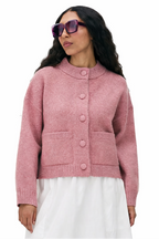Woman wearing a pink cardigan and white skirt on a white background